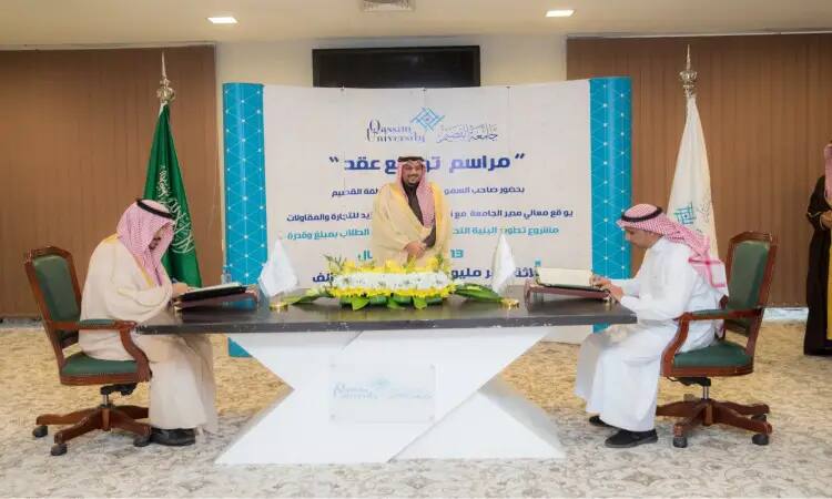 يجلس ثلاثة رجال مرتدين الغترة أو الشماغ مع العقال والبشت السعودي حول طاولة، يوقعون وثائق خلال مناسبة تُعنى وتأثير الذكاء الاصطناعي. وخلفهم شعار جامعة القصيم، بالإضافة إلى علم المملكة العربية السعودية وعلم أن شعار العصر الأبيض مميزًا.