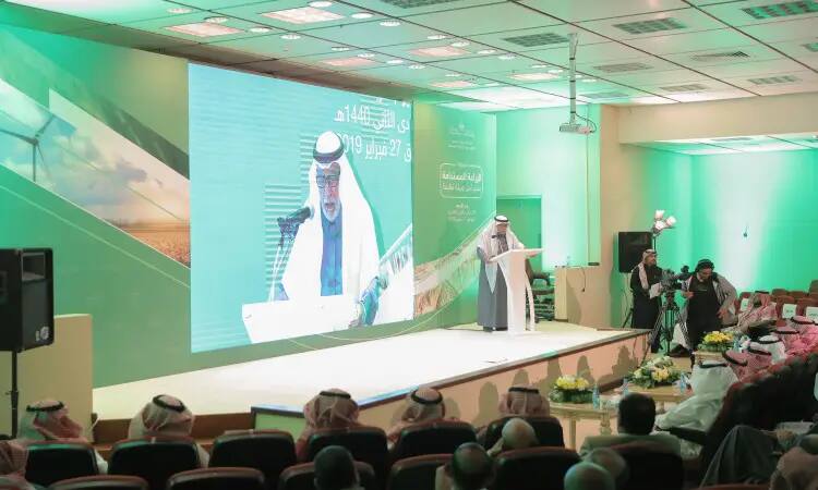 A man dressed in a Saudi yaghtar and a headband with an elegant Saudi shawl takes the stage in the modern, green man-decorated conference hall at Qassim University and delivers a keynote address to the audience, highlighting the highlights of the agricultural sector and emphasizing the importance of sustainability in enhancing the future of the industry.