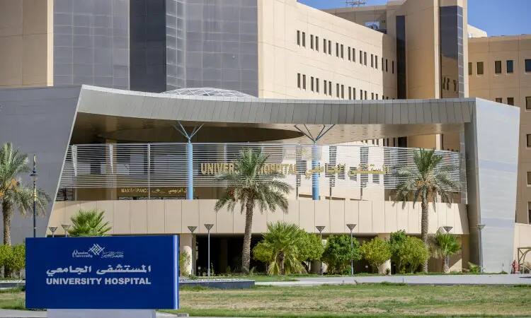 The Medical City Hospital building in Qassim is modern, surrounded by a palm tree on the home page. The entry is topped with a blue sign that reads "UNIVERSITY HOSPITAL" in both English and Arabic. Characterized by beige walls and large windows, the hospital is known for its role as a sponsor of medical excellence in a sophisticated setting.