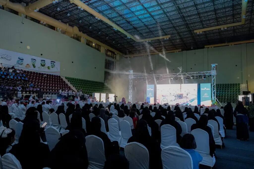 A large crowd of attendees swarmed into the ranks of the White Chairs Organization and descended on a brightly lit stage inside the Ahlan Hall during the Seventh Summer Club at Qassim University. Many of the candidates from the university are recognized by the audience as wearing the Saudi Shemagh, or Ghutra and Eqbal, as well as the Saudi Bisht, confirming the accuracy of the print and the national identity of the event. The place is filled with patrons who have come to participate in this prestigious university event.