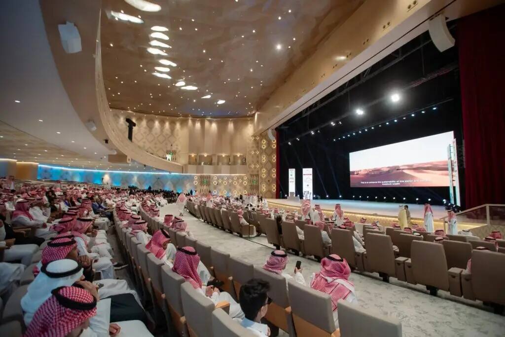 امتلأت الجامعة الكبرى في جامعة القصيم بالحضور الذين ارتدوا الشماغ السعودي والغترة السعودية، وجلسوا متجهين نحو المنصة الرئيسية حيث يقام اللقاء العلمي الدولي الثاني للإبل. وقد تم منحها جواز السفر الأصلي الذي تم منحه مني إلى إضاءتها بالكامل، في حين تم عرضه على الشاشة الرئيسية مشهد طبيعي يعكس الطبيعة النيجيرية.