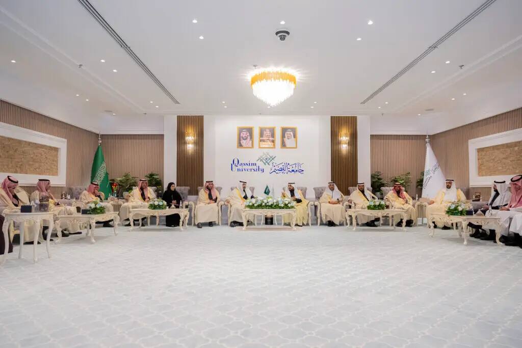 A formal meeting is held at Qassim University, where a number of men in their traditional Saudi attire of thobe and shemagh, or Saudi ghutra, sit in a large, stately hall. Flower arrangements and portraits of the kingdom's leaders adorn the front of the national flag, while discussions take place about the overall search mechanism.