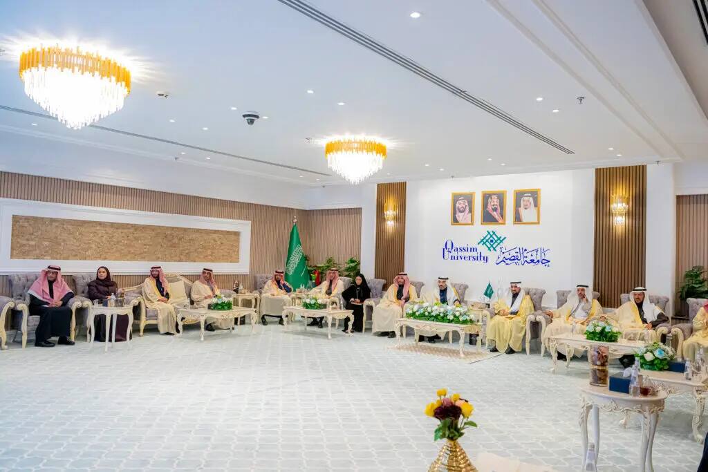 A formal meeting at Qassim University brings together men and women in authentic Saudi dress, with the men wearing the Saudi shemagh or ghutra. The meeting takes place in a luxurious ballroom with a shiny ceiling, whose walls are decorated with pictures and the flag of Saudi Arabia. Attendees implicitly discuss respect for national character and adherence to national values.