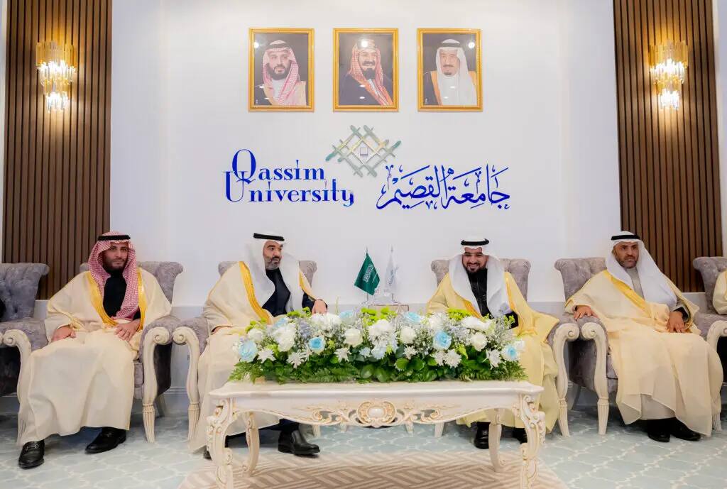Four men wearing the Saudi shemagh or Saudi ghutra sit on plush chairs at Qassim University, surrounded by a bouquet of flowers and topped with images of non-Saudi Arabia, in a scene that epitomizes the role of the entire university as a research institution.