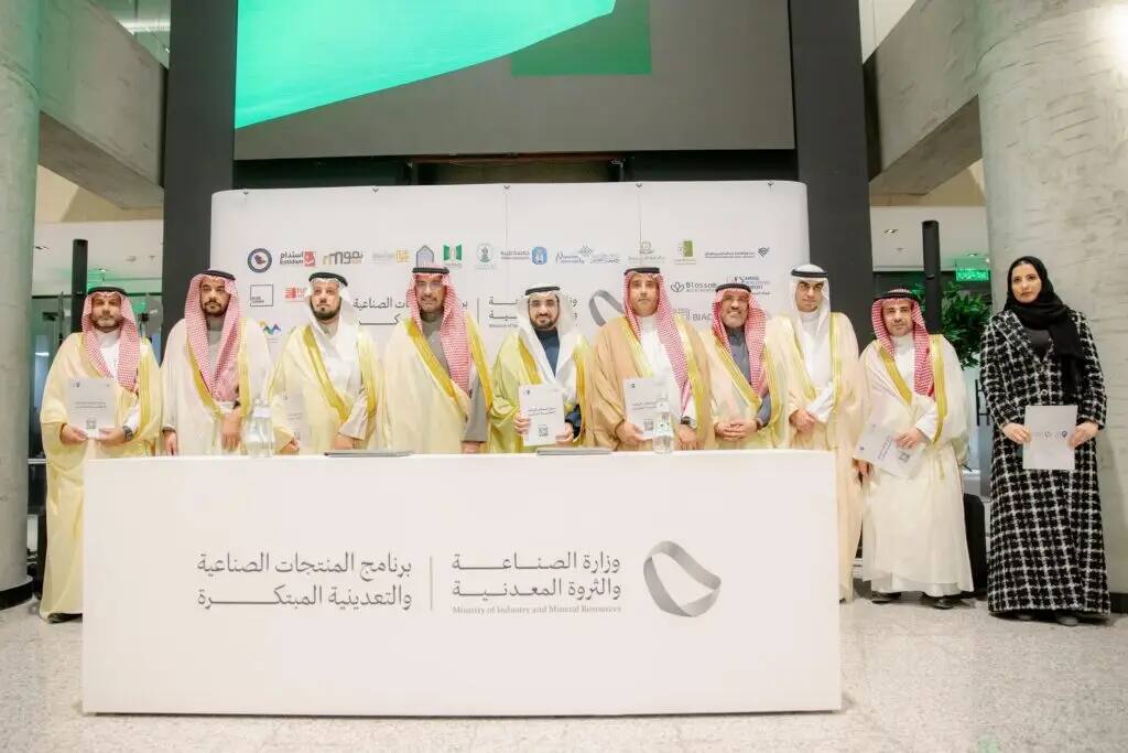 A number of men dressed in Saudi uniforms, including a woman in a black dress, stood behind a menu selling a number of files, emphasizing the support of innovators and the development of industry. Contribute to the logo of the Ministry of Industry and Mineral Resources in both Arabic and English.