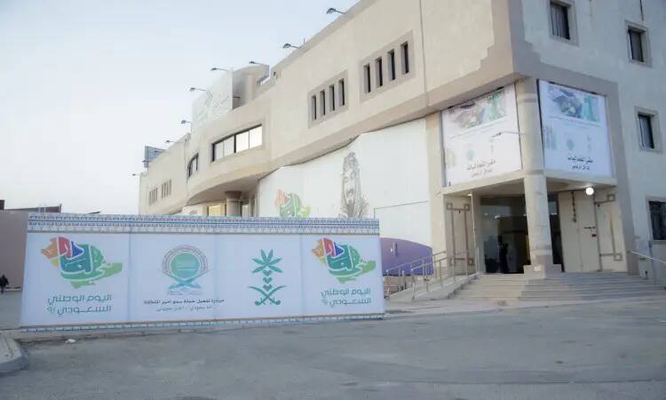 مبنى جامعة القصيم الحديث بلونه الأبيض، يكتسي حُلّة خاصّة تليق بمكانته الأكاديمية. تتزين صفحة بلافتات باللغة العربية، من جملة "أنا سعودي أعتز بهويتي" وشعارات اليوم الوطني. يؤدي ممراً مخصصاً إلى المدخل الرئيسي حيث يبرز أمامه لوحة جديدة جديدة "سمو أمير المنطقة". وتمثل مظاهر الاحتفاء الرسمي بالحضور شماغ سعودي وبشت وقال في صور الحضور والافتات النظيفة، أثناء ظهور الساحة ومضيئها بما في ذلك يعكس الرقي.