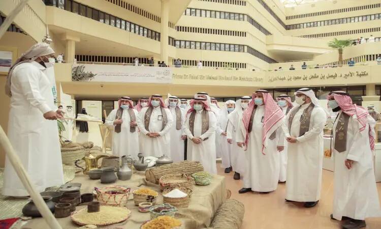 يجتمع مجموعة من الأشخاص تولى الزي السعودي الأصلي، بما في ذلك رئيس الجامعة الذي ارتدى الشماغ والعقال والبشت السعودي، لمتابعة معرض يوم تانكس في ردهة الداخلية الحديثة، والذي يشتمل على مأكولات وتحف تستعرض جانباً من تاريخ الدولة السعودية. كامل الحضور ملتزمون بارتداء الكمامات الطبية، بينما يقوم أحد المشاركين بإلقاء كلمة من خلف طاولة العرض.