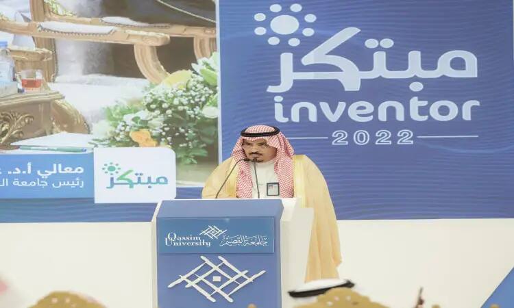 رجل يرتدي الغترة السعودية والعقال والبشت السعودي يُلقي كلمة من على المنصة خلال معرض المبدع 2022 في جامعة القصيم. ينصح في الخلفية لافتة باللغتين العربية والإنجليزية، تحتفي بالطلبة المبتكرة.