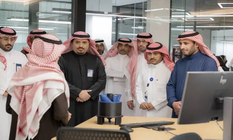 يجتمع مجموعة من الرجال مرتدين الغترة أو الشماغ والعقال بالإضافة إلى البشت السعودي في مكتب بمعمل كود الجامعة، حيث يجتمعون باهتمام شخص واحد ويتبادلون النقاشات حول ريادة الأعمال الرقمية من مكتب يحوي شاشة الكمبيوتر وبعض المستلزمات المكتبية.