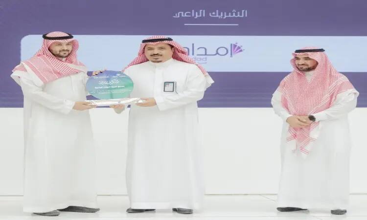 Three men painted on the stage during the "Technical Career Day" events in Qassim, holding the white Saudi robes, wearing the Saudi ghutra or Saudi shemagh with the headband, while one of them is wearing the Saudi bisht. One of the men is holding a blue honorary shield presented to him by the man standing on his left, while the third man next to them is smiling in a scene that reflects the spirit of celebration and formality in this scientific academy.