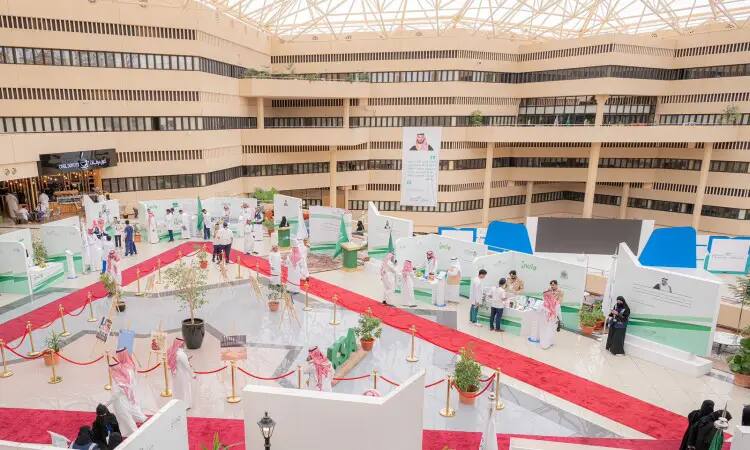 Maintaining the interior of the exhibition required with banners, displays, and carefully organized tables. Dressed in the Ghutra or Shemaghogal, as well as the Saudi Bisht, they exchange conversations about the Wai2 exhibition, which highlights the efforts to combat the coronavirus. A red carpet and ornamental plants decorate the space, while a large picture of a prominent man sits in the center of one family, giving the appearance of an official with the prestige of Qassim University.