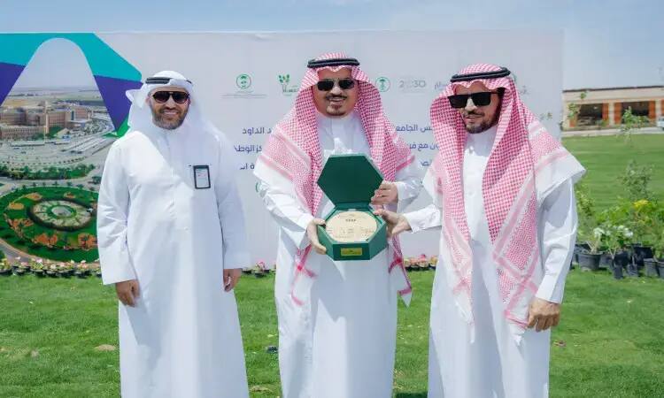 الاتصال ثلاثة رجال مرتدين الغترة أو الشماغ والعقال، وتتميز برأس الجامعة في المنتصف بارتدائه البشت السعودي ويحمل درعًا تكريمًا داخلها. لإعدادها خلفهم لوحة تحمل نصوصًا باللغة العربية من بالإضافة إلى "لنجعلها خضراء" وشعارات متعددة مع تنسيقات جمالية لافت للأزهار الملونة المزروعة في.