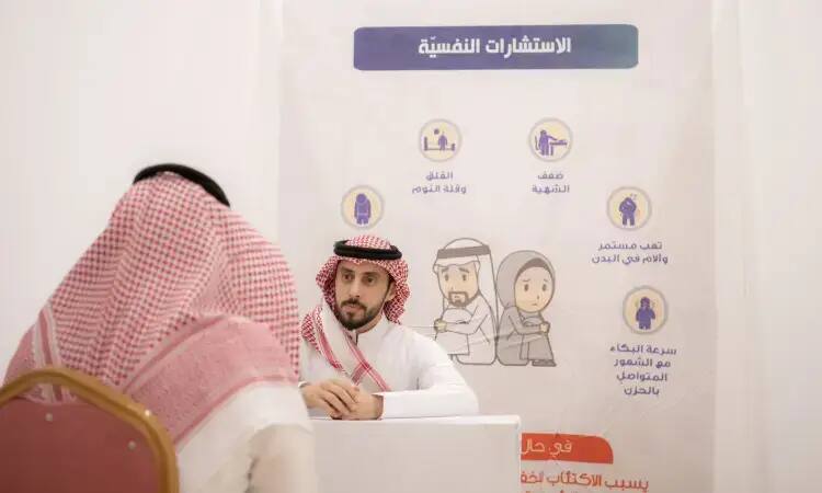 يجلس الرجل مرتدياً الغترة السعودية والعقال والبشت الرسمي على الطاولة، ويتحدث مع رجل آخر يظهر ظهره للكاميرا. إذ يبرز في الخلفية ملصق مركز يبرز أهمية الحملة النفسية، ويركز على محور التوعية الصحية والتثقيف بين منسوبي وطلاب جامعة القصيم.