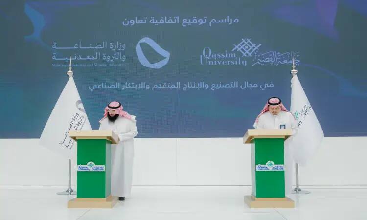 Two men wearing the Saudi Ghutrah, Eqal and Bisht at two microphone stands, signing the cooperation between the Ministry of Industry and Wealth and Qassim Mineral University. The selection of logos and banners of participating components, including advanced industrial production logos, is recommended.