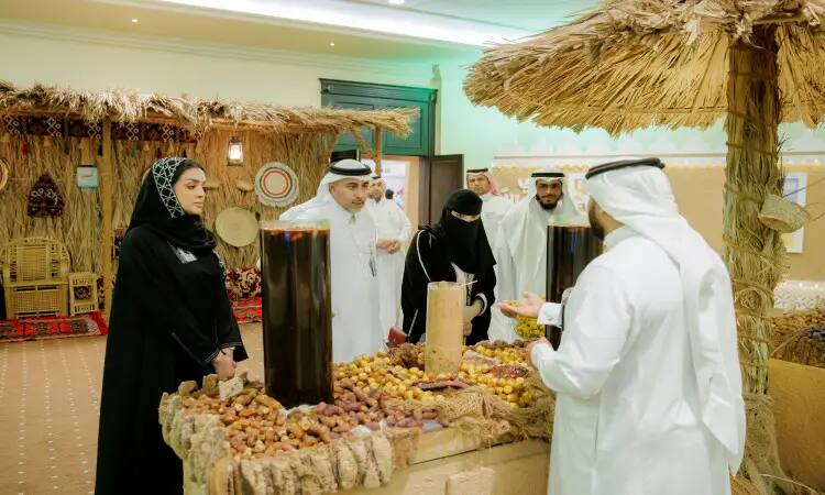 A number of people in Saudi Arabian ghutra, shemagh, aqal and bisht gathered around a unique display of dates and harasar as part of the Buraydah Dates Carnival, decorated with carefully woven straws and baskets. The university's exhibit was thoroughly explained by someone who emphasized the importance of local products and Qassim University in supporting them.
