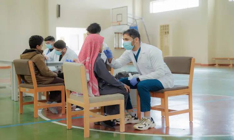 A health practitioner wearing a white coat and medical mask takes a nasal sample from a person at a senior center as part of efforts to promote health awareness and community education. Wearing neither the Saudi ghutra nor the medical mask during the procedure, the health practitioners change roles while wearing the masks. This initiative from Qassim University embodies its keenness to provide a safe and healthy environment for all their guests, and to reflect the Swedishness through the besht, headband, and ghutra.