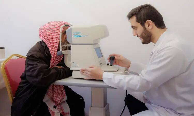 Wearing a white coat, an eye care attendant at the Dukhna Center examined the eyesight of a patient wearing a Saudi Arabian tunic, headband, and bisht. This is part of the frequent health promotion of the level of awareness about vision health, including in line with the efforts of Qassim University in serving the community and spreading health culture.