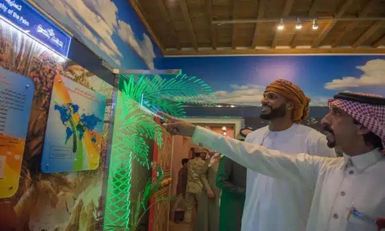 رجل للاتصالان يرتديان الغترة أو الشماغ السعودي مع العقال، وتتميز بارتداء البشت السعودي التقليدي، يتأملان بانتباه عرضاً مضاءً حول التمور والنخلة. ولذلك السبب يجب أن نرسم خريطة بالأضواء الخضراء الزاهية داخل قاعة المعرض الجنادرية النباهة بالحيوية، وذلك في إطار فعال للأطفال تقيمها جامعة القصيم.