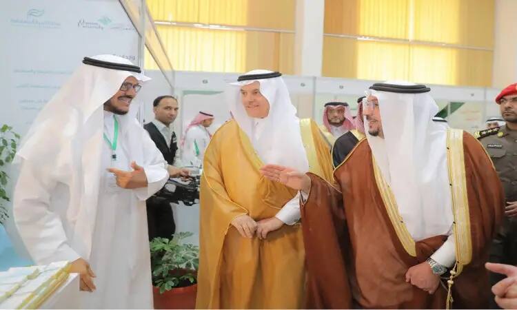 يتبادل مجموعة من الرجال مرتدين الغترة أو الشماغ والعقال، ومُرتدين البشت السعودي، أطراف الحديث ويوجهون الخيمات خلال أُقيمت في مدينة بريدة، حيث يناقشون فرص الاستثمار الزراعية الزراعية. يشارك أحد بالإشارة بيده بينما يصغي الباقون باهتمام، ويشترك في التأمين في الخلفية على النظام.