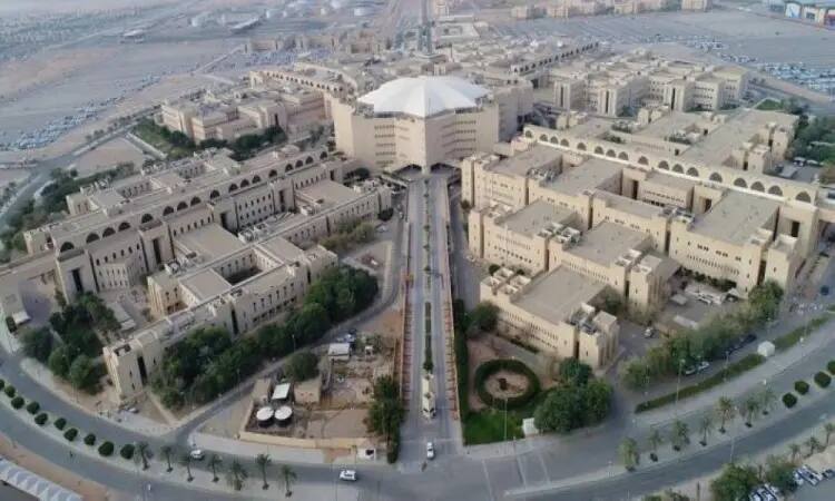 A modern aerial view of Qassim University, where symmetrical residential buildings are distributed around a centralized central facility, surrounded by organized facilities and green spaces amidst a desert environment. This distinctive location offers a new version of a women's driving school, with female students and administrative staff dressed in the Saudi Ghutra or Shemagh, Egal, and Saudi Besht, including the official university and local unions.