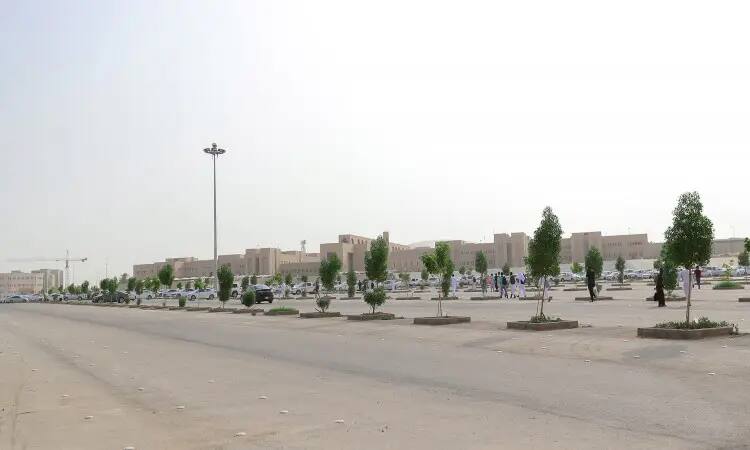 مشهد بانورامي لمواقف سيارات واسعة في جامعة القصيم، تتخللها مجتمع متفرقة ضمن تبرعات تشجير المواقف السيارات. عدة سيارات متوقفة وقلة من الأشخاص الغتيرة السعودية أو الشماغ والعقال والبشت السعودي يسيرون بهدوء في أرجاء المكان. وفي هذه القضية تبرز مباني الجامعة المتعددة الألوان، تحت سماء تغشاها بعض الضبابية.