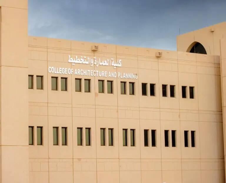 يتميز المبنى ذو اللون المناسب لكلية الهندسة المعمارية والتخطيط في القصيم بصفوف من النوافذ الدائرية، ولوحات تعريفية مكتوبة باللغتين العربية والإنجليزية، وذلك تحت السماء يغلب عليها الغيوم.