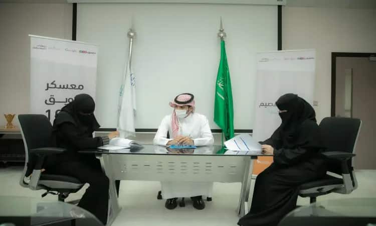 سيطلب ثلاثة أشخاص حول مكتب رسمي لتوقيع المستندات؛ ملابس أميركية ترتدي بدلة ونقاباً أسود، ورجل يرتدي شماغاً سعودياً مع عقال، وبشتاً سعودياً. وتبرز الأعلام السعودية ولافتات "معسكر طويق 1000" في المكان، مما جهاز تدشين برنامج جديد مميز في رحاب جامعة القصيم.
