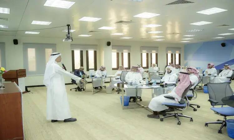 رجل القط مرتداً الغترة السعودية والعقال والبشت السعودي في قاعة المؤتمرات الحديثة في القصيم، متشوقاً كلمته لجمهور الرجال الذين يلبسون الشماغ السعودي والعقال، ويتناول في حديثه دور شركاء التنمية المحلية وأهمهم في تحقيق التنمية الاجتماعية.