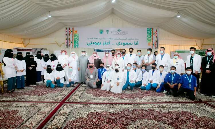 The photo shows a large group of men, many of them wearing medical uniforms and protective masks, and a group photo inside a tent decorated with women and Arabic logos at the university's pavilion in Qassim across the Sharq at the Buraydah Spring Festival. Some of the men are in charge of the Saudi Pashtuns and are adorned with the shammaa or aqal and the Saudi Ghutra, while a number of women wear abayas and jababs in a formal manner that follows the prestige of the university and the events of the region.