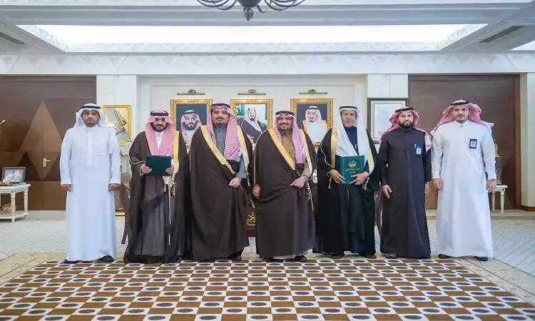 Men dressed in formal Saudi attire, including the Ghutra or Saudi Shemagh and Egal, as well as the traditional Saudi Bisht, lined up in a luxuriously decorated interior hall and a head hung in. It aims to create files following the signing of a memorandum of understanding at Qassim Medical City, under the patronage of the Emir of Qassim.