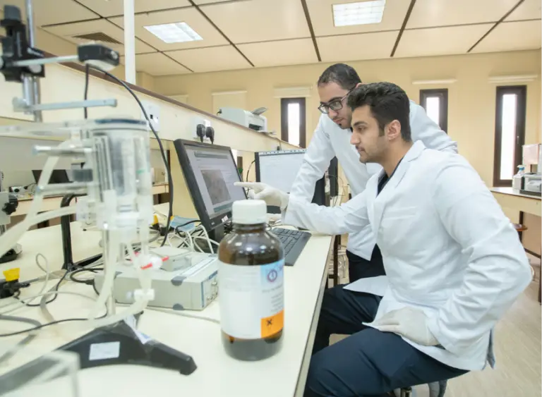 يعمل عالمان متعاطفين مع المختبرات الثنائية في أحد المختبرات النموذجية التابعة لمراكز الأبحاث في القصيم. ويظهر على منضدة تجهيزات مخبرية حديثة وزجاجية ومواد كيماوية. يجلس أي شخص يستخدم الحاسوب بينما يلتقط الآخر شماغاً سعودياً، ويختار إلى شاشة الكمبيوتر ضمن مناقشة علمية متخصصة.