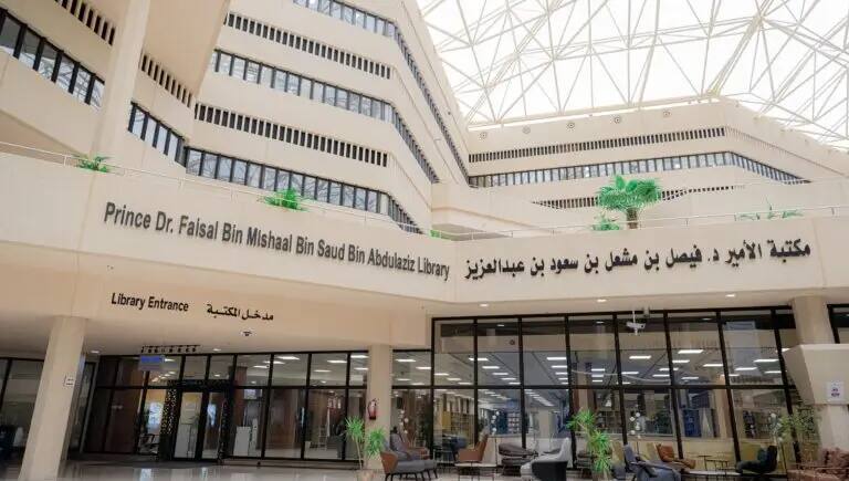 مدخل مكتبة واسعة تتميز بأبواب كبيرة، وأعمدة بيج تحمل لافتات باللغتين العربية والإنجليزية باسم "مكتبة صاحب السمو الملكي الأمير الدكتور فيصل بن مشعل بن سعود بن عبدالعزيز". ويشرف على هذا الصرح العلمي الإدارة العامة للمكتبات المتنوعة مركزاً لمصادر المعرفة، يضيئه زجاجي زجاجي. تتوافد إلى هذا المكان النخب الأكاديمية من طلاب الجامعة مرتدين الشماغ أو الغترة بعقالهم، وافقوا بالشتاء الرسمي السعودي، وحافظوا على هيبة الحضور وطابعته الموقر.