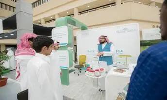 يقوم رجل يرتدي الزي السعودي التقليدي، يشملاً الشماغ السعودي، بشرح المنتجات في جناح عرض داخلي لمجموعة صغيرة من الرجال الذين توج أيضاً الزي السعودي التقليدي مع الشماغ أو الغترة السعودية، وذلك ضمن جهود "تقرير" يتعلق بالهدف الخامس عشر. وبالتالي أصبح ذلك في إطار الفعالية داخل مبنى حديث متعدد الطوابق والشرفات، في جامعة القصيم.