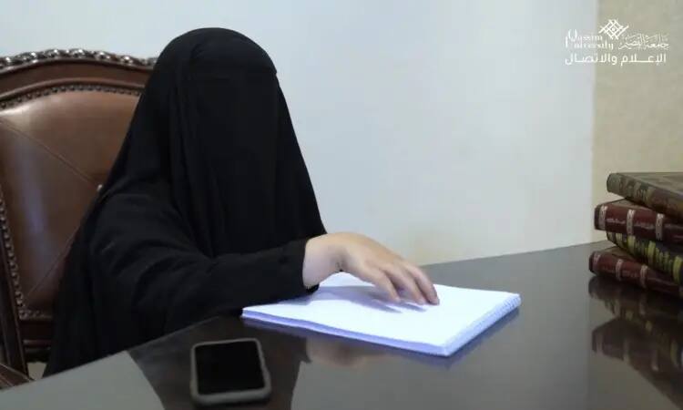 A man wearing a black niqab reads a book written in Braille on a desk, with a smartphone and several large books stacked nearby. The Qassim University logo and the "Tenth Objective" slogan appear in the upper right of the report.