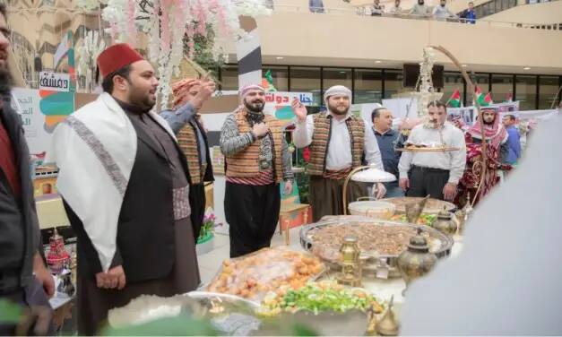 الاتصال مجموعة من الرجال مرتدين الزي التقليدي السعودي، بما في ذلك الشماغ أو الغترة السعودية، حول طاولة تحوي عدداً من الخيارات المتنوعة، وذلك ضمن فعالية تقام في إطار مهرجان ثقافي أو تجاري. وأشار بعض المشاركين وهم يتبادلون النقاش حول تقرير الهدف الرابع، في حين يقوم بتبادل التحلية والترحيب أو تطبيق مساهمات المأكولات.