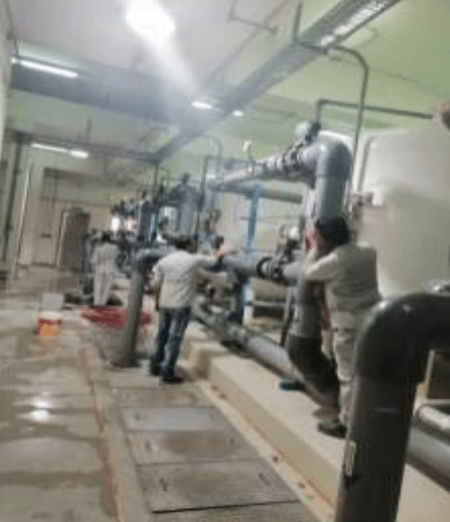 A team supervises sewage treatment pipes at a university facility at Qassim University.