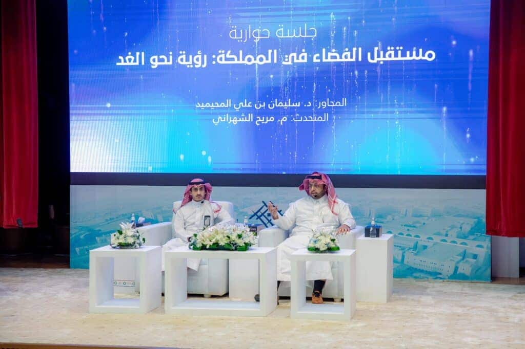 مشاركان في نقاش علمي على مسرح جامعة القصيم ضمن فعاليات أسبوع الفضاء العالمي.