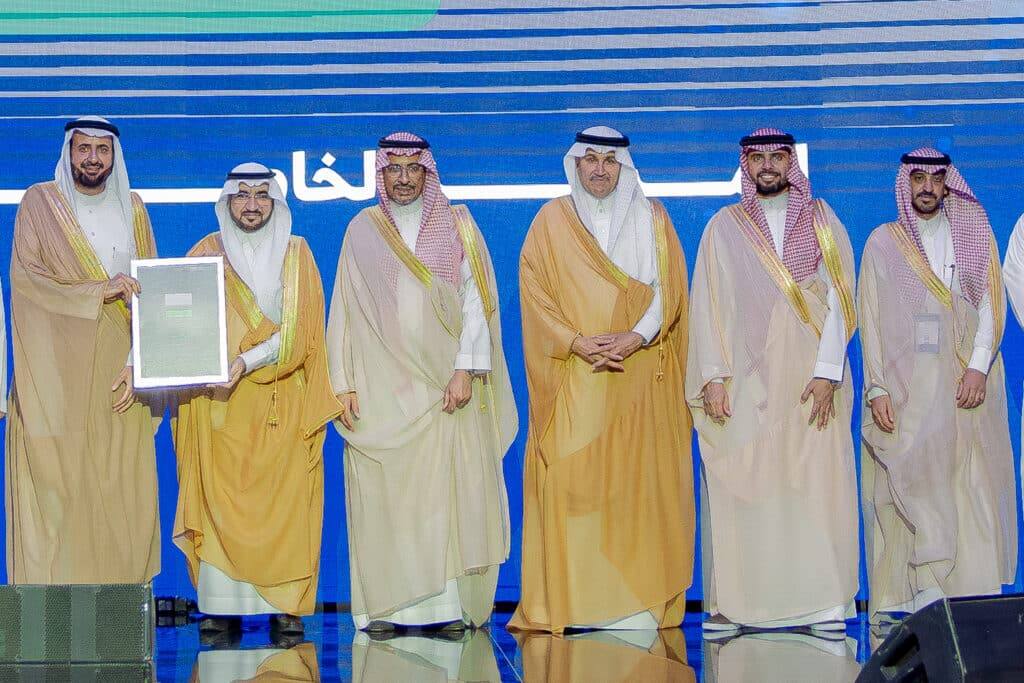 Honoring an academic at Qassim University in the presence of faculty members, wallpaper with the university logo.
