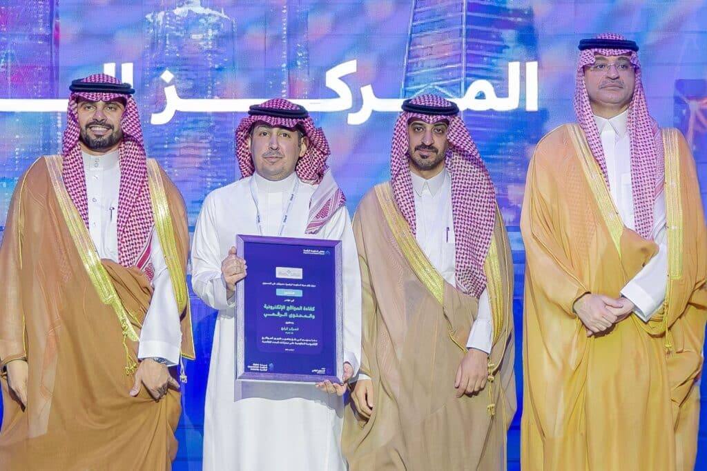 تكريم أكاديمي بجامعة القصيم بحضور أعضاء الهيئة وتكريم أحد المتفوقين على المنصة.