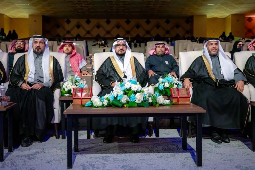 لقاء أكاديمي في جامعة القصيم بحضور قيادات وأعضاء، وتزيين للقاعة بزهور وكتب.