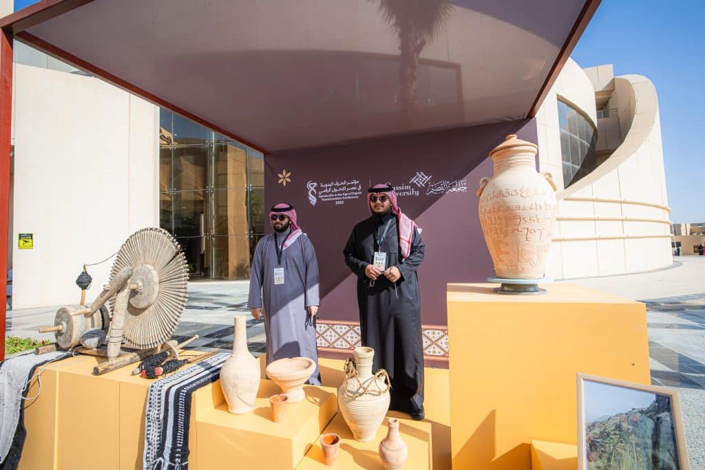 A display of Saudi handicrafts at the Qassim event with a modern architectural backdrop.