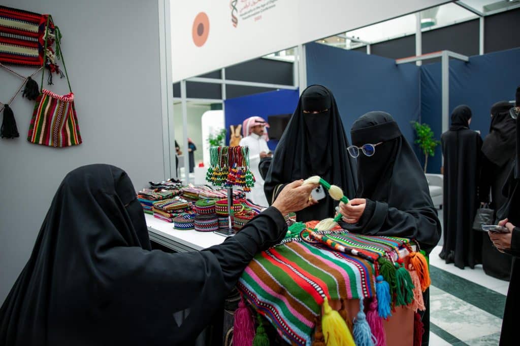 Cultural interaction in a handicraft market at a university event at Qassim University and the exchange of local products.