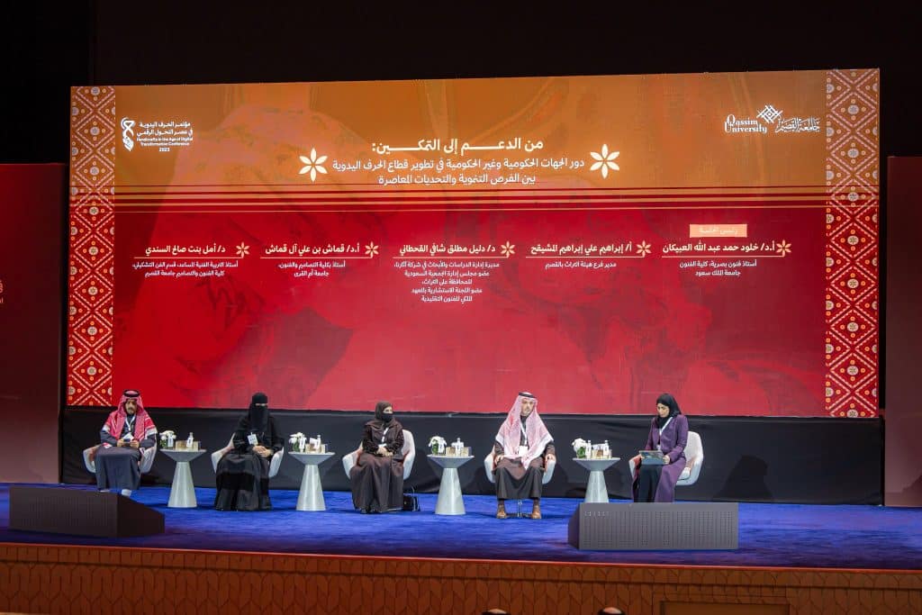 An academic academic discussion at Qassim University featuring speakers in front of an orange background with Arabic text.