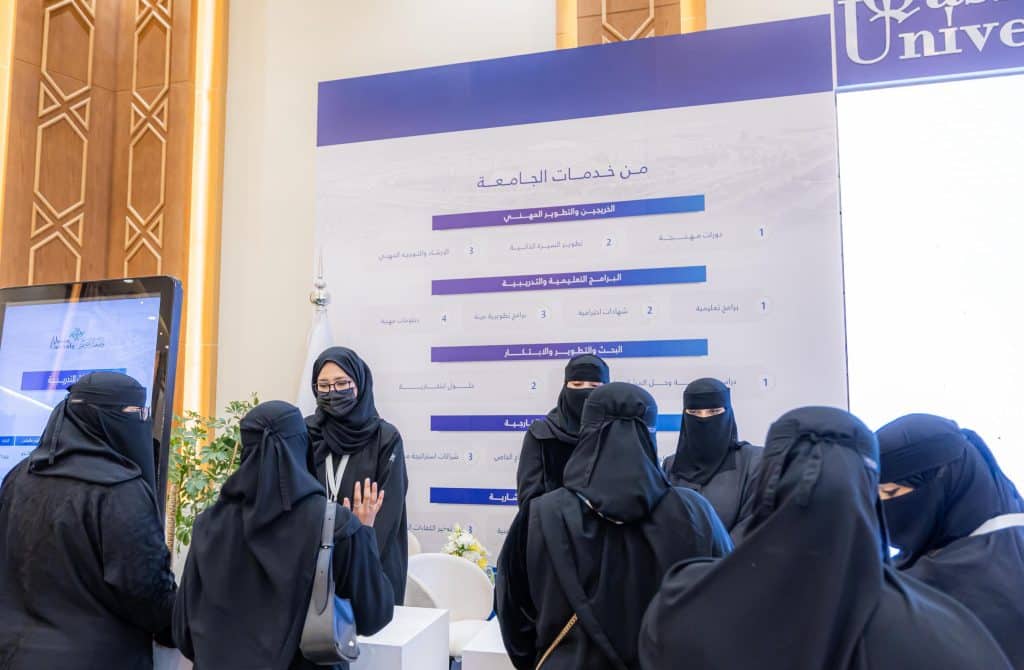 Qassim University students discuss at the My Pavilion pavilion during an academic event.
