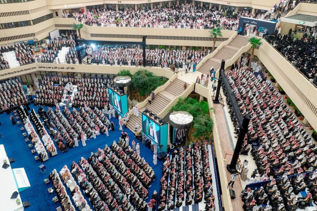A large hall at Qassim University hosts an academic event with a large attendance and an organization that reflects the Saudi identity.