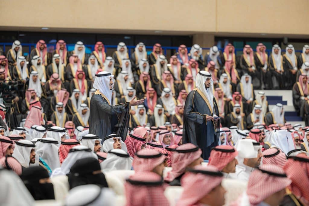 A formal academic ceremony honoring Qassim University graduates in a hall dedicated to university events.