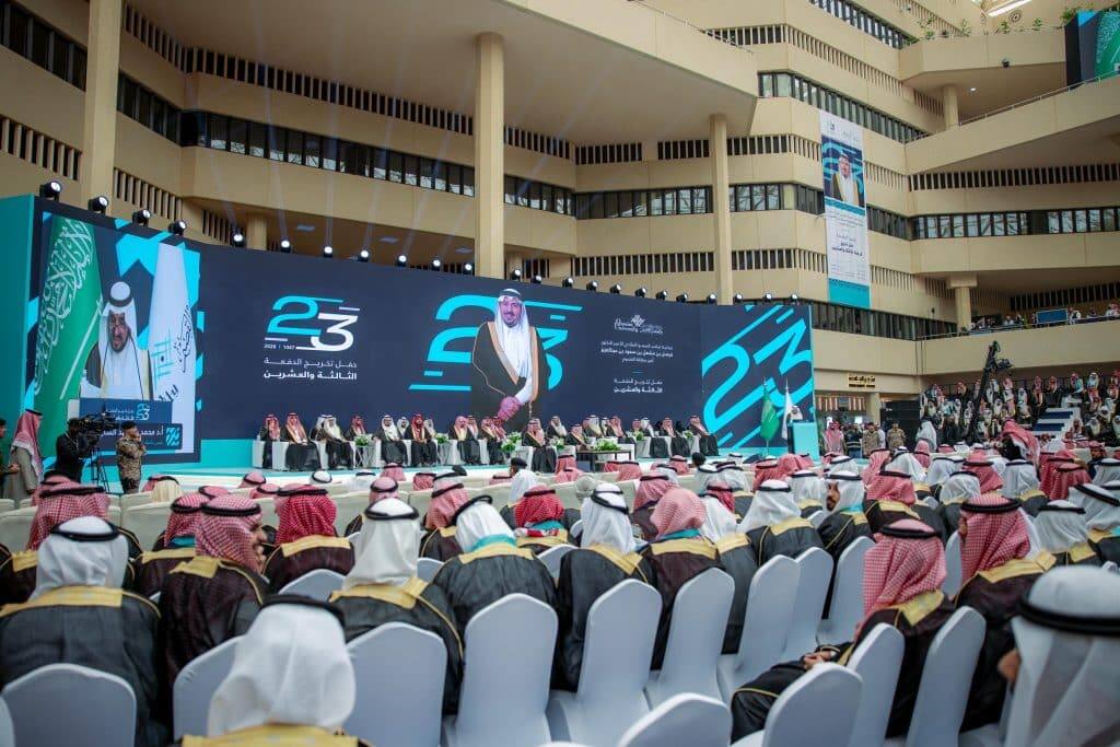 Outdoor graduation ceremonies at Qassim University with digital screens and an official platform.