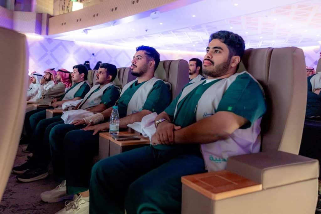 Qassim University's graduation ceremony with students watching the event in Haditha Hall.