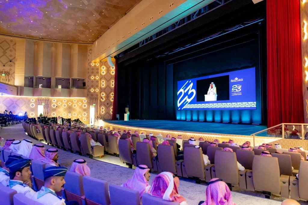 An official graduation ceremony at Qassim University in the presence of the university president and the event's logo screen.