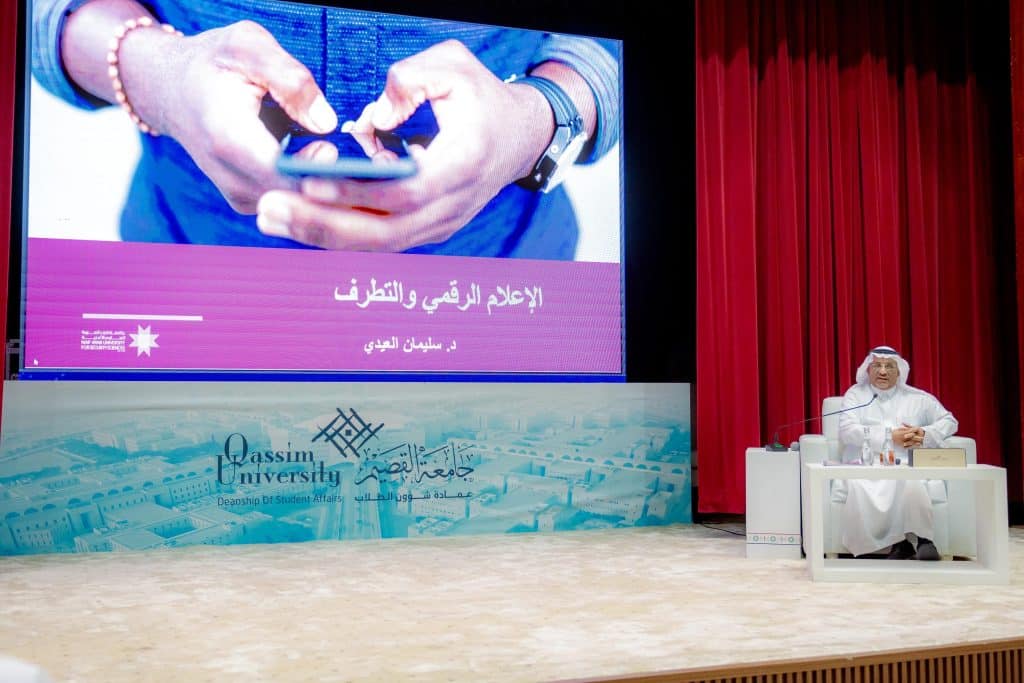 A participant is giving a presentation on media at an academic event at Qassim University.
